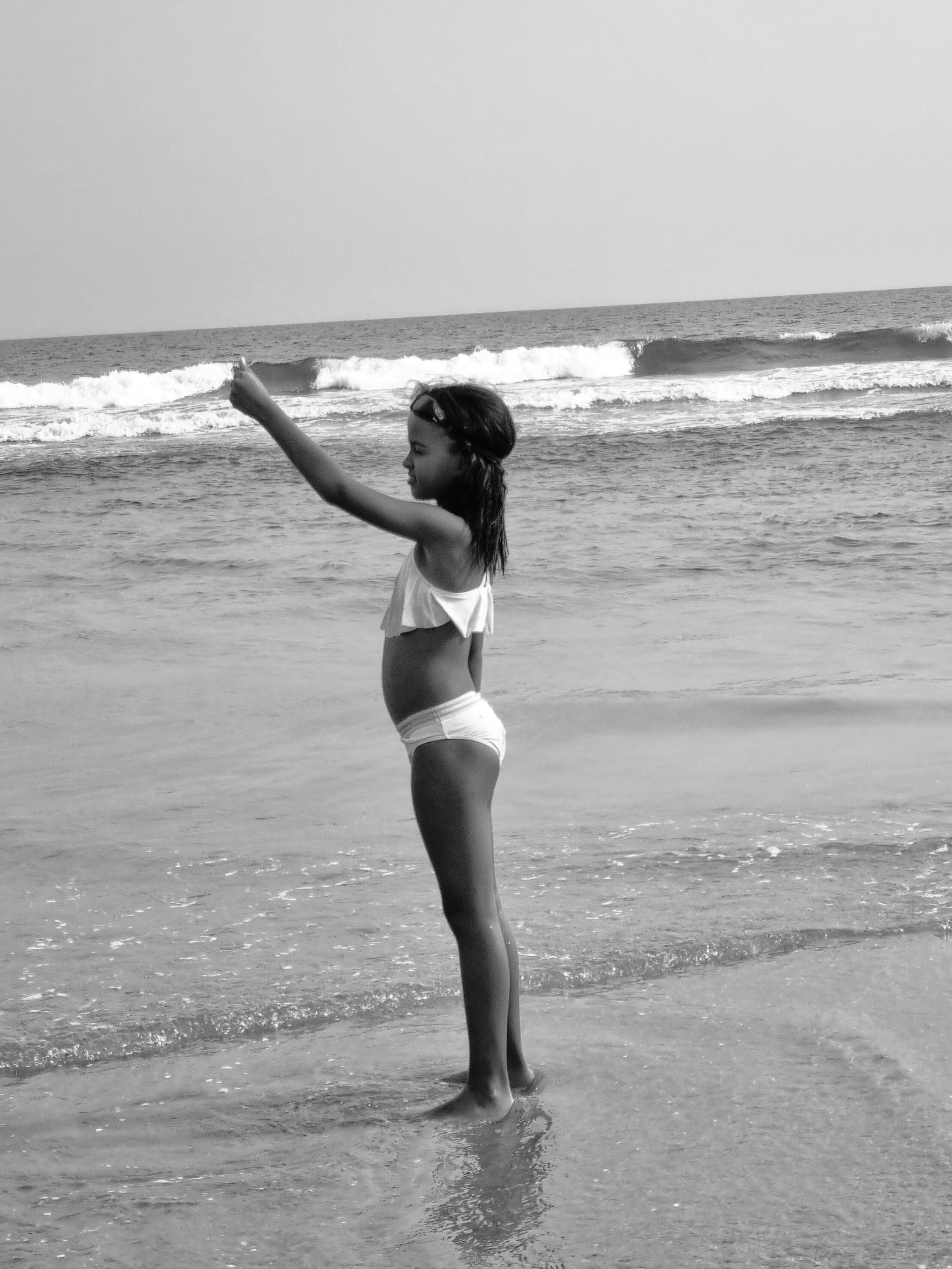 A young girl standing at the edge of the ocean