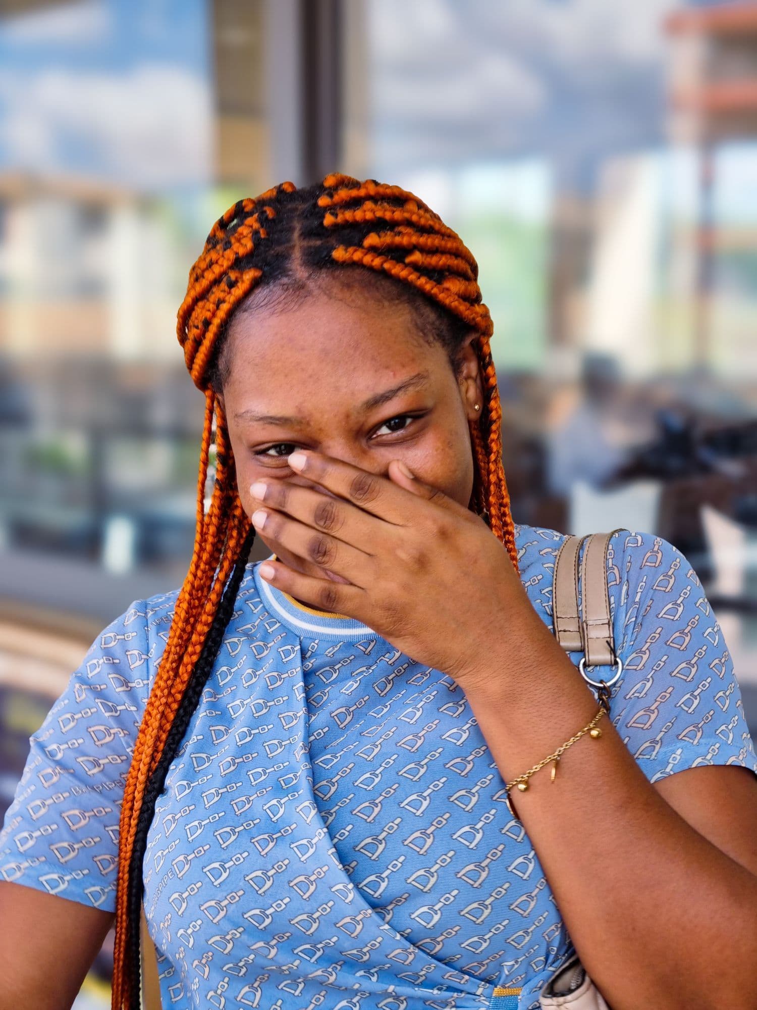 Woman with orange braided hair covering her smile